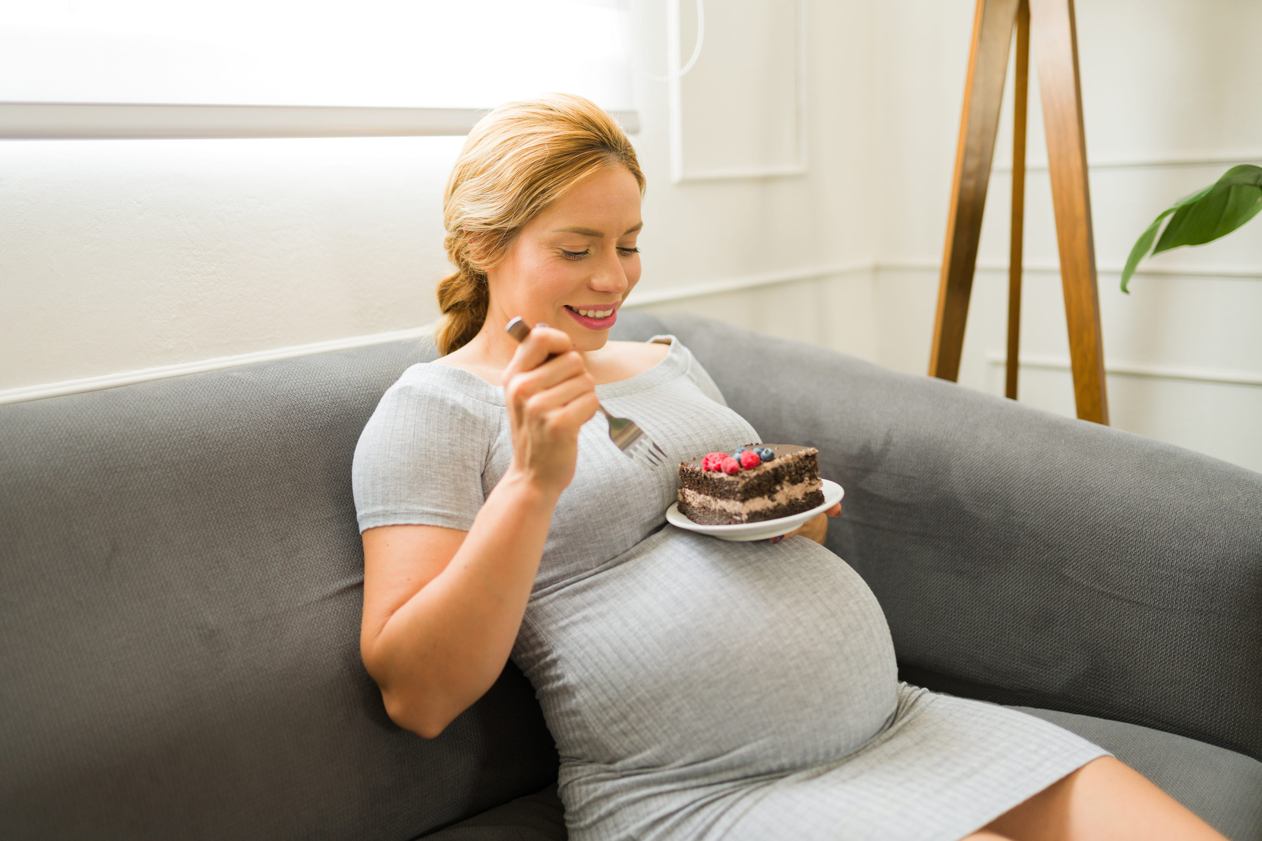 Mujer joven embarazada comiendo un postre dulce.