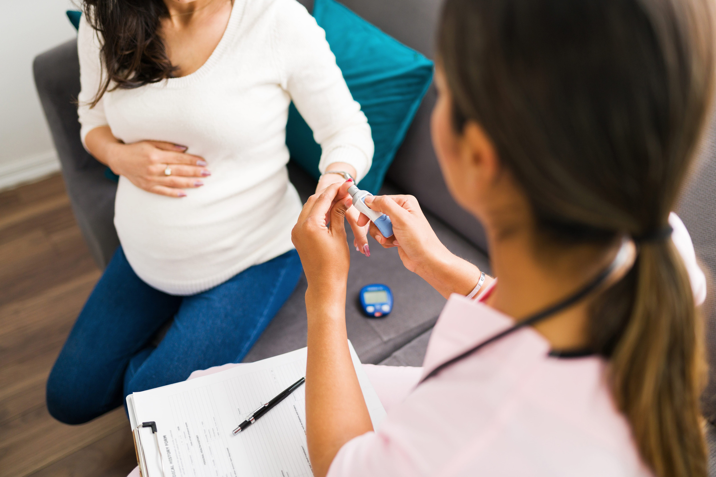 Una doctora tomando un examen rápido de glucosa a una mujer embarazada.