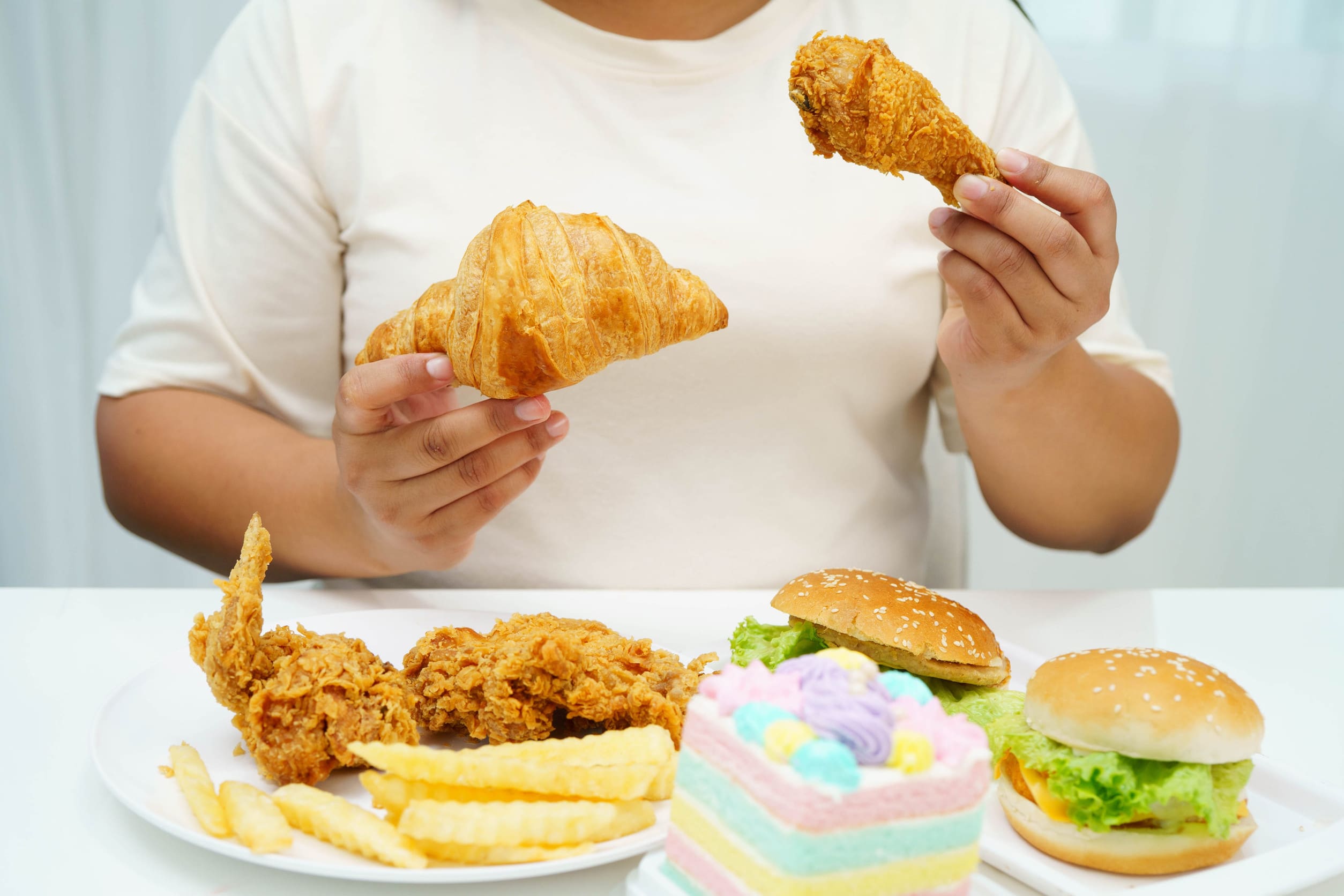 Persona comiendo alimentos grasos que provocan acidez estomacal.