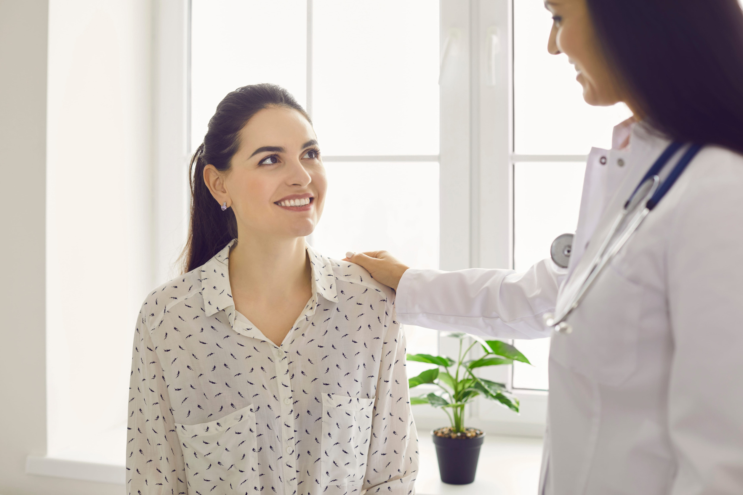 Mujer joven sana y sonriente junto a una profesional de la salud.