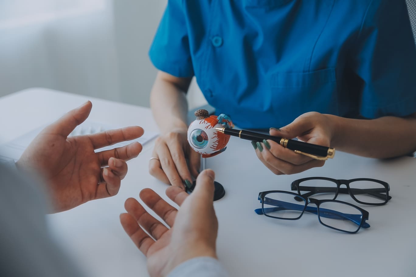 Un oftalmólogo explicando a un paciente el glaucoma usando un modelo de ojo.