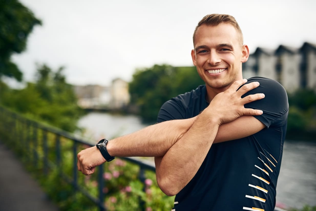 Hombre joven con una sonrisa mientras se prepara para hacer ejercicio físico.