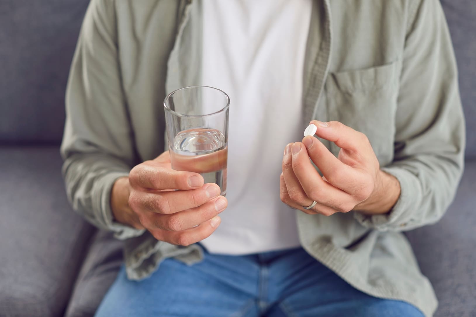 Persona tomando una pastilla con un vaso de agua, siguiendo el tratamiento antibiótico indicado por su médico