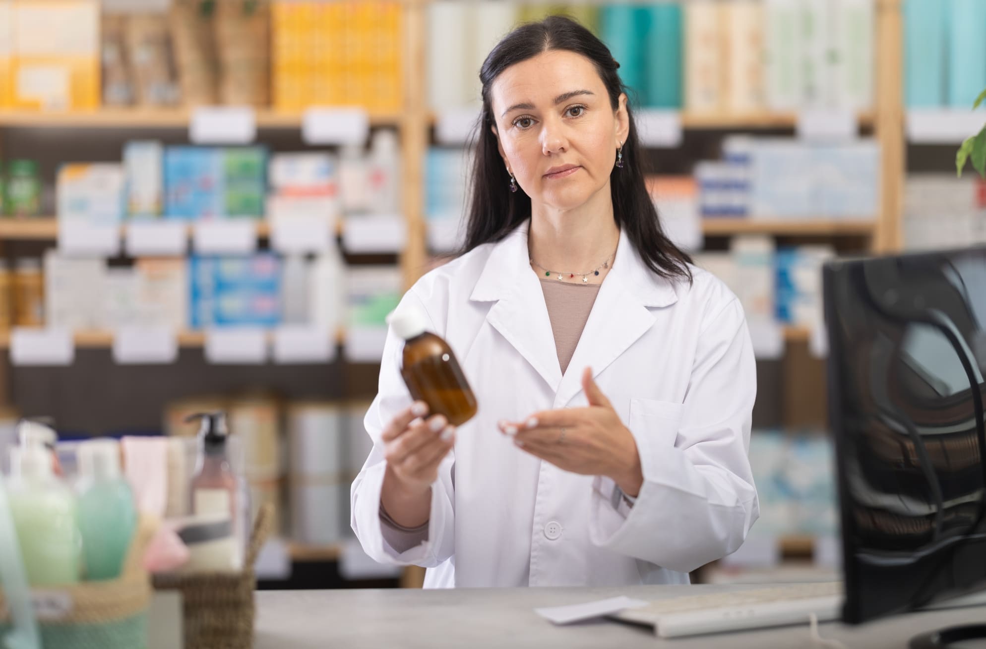 Farmacéutica mujer en el mostrador con un medicamento en sus manos.