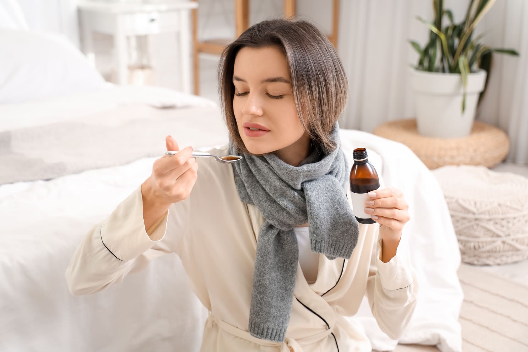 mujer-con-bufanda-tomando-jarabe-para-la-tos-y-resfriado