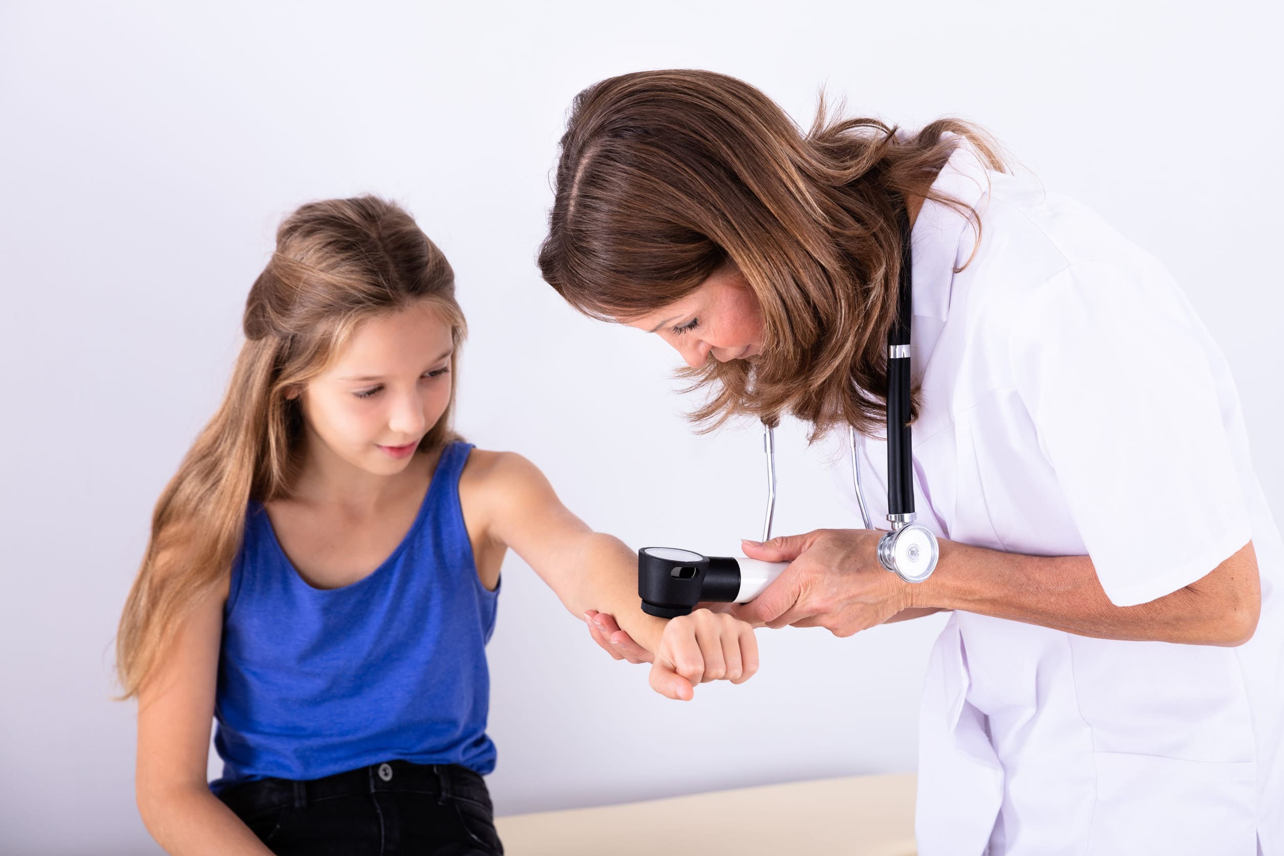 Primer plano de una niña a la que revisan la piel con un dermatoscopio.